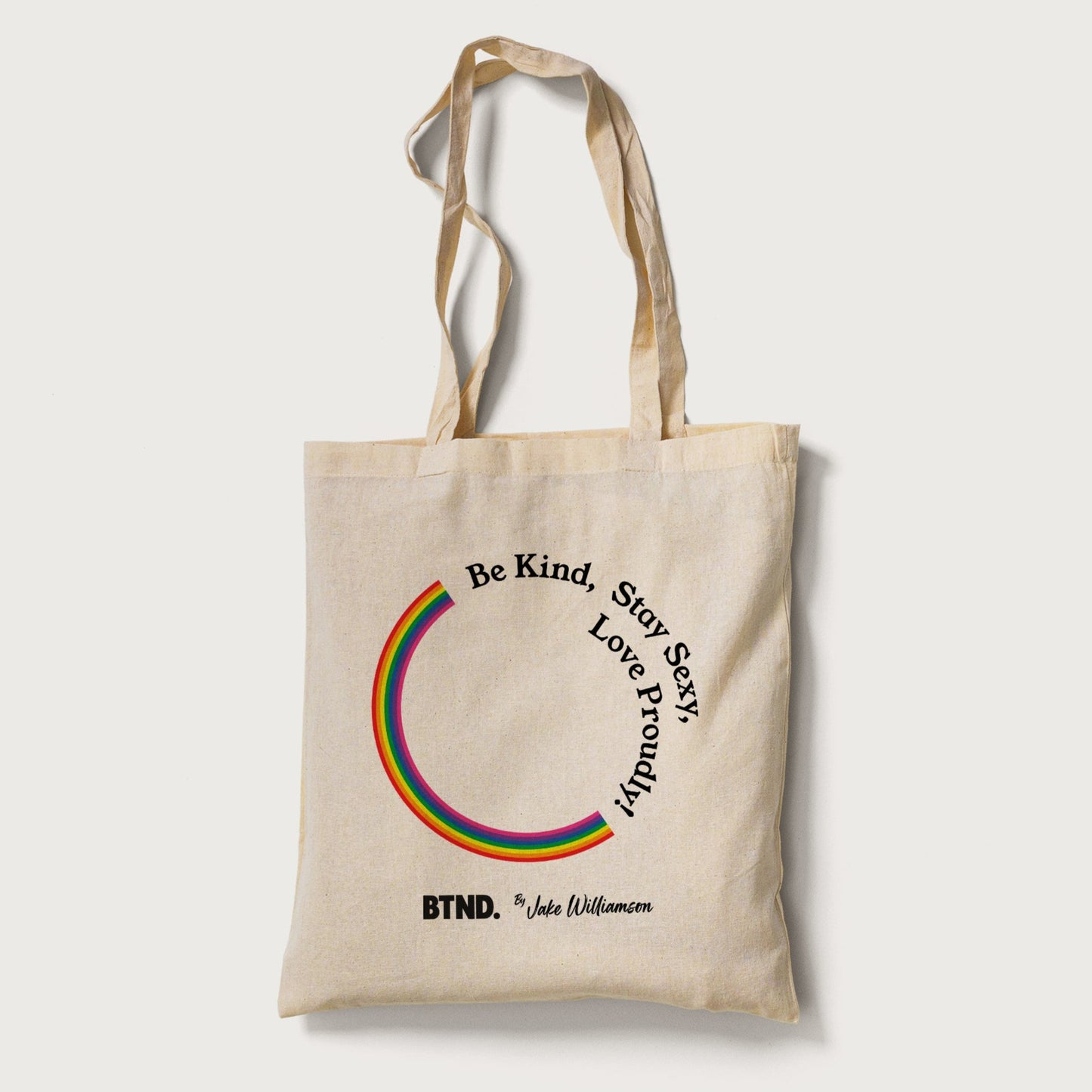 Beige tote bag with rainbow design and text on a white background